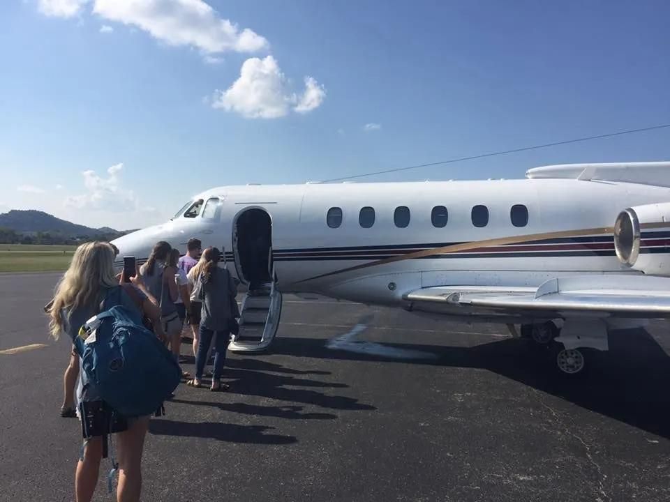 People boarding a white private jet on a tarmac.