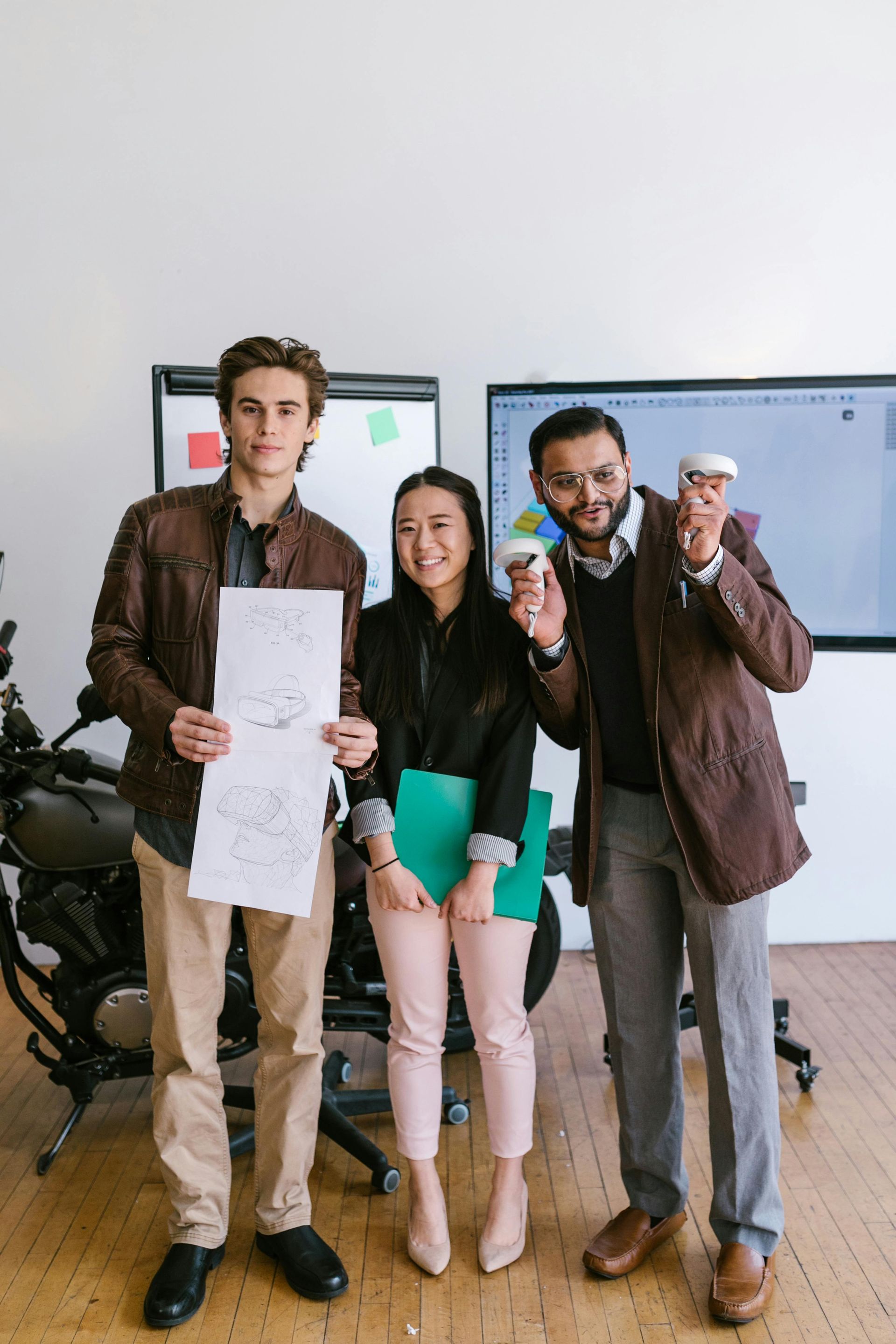 Three people seated at a wooden table in an office, discussing documents.