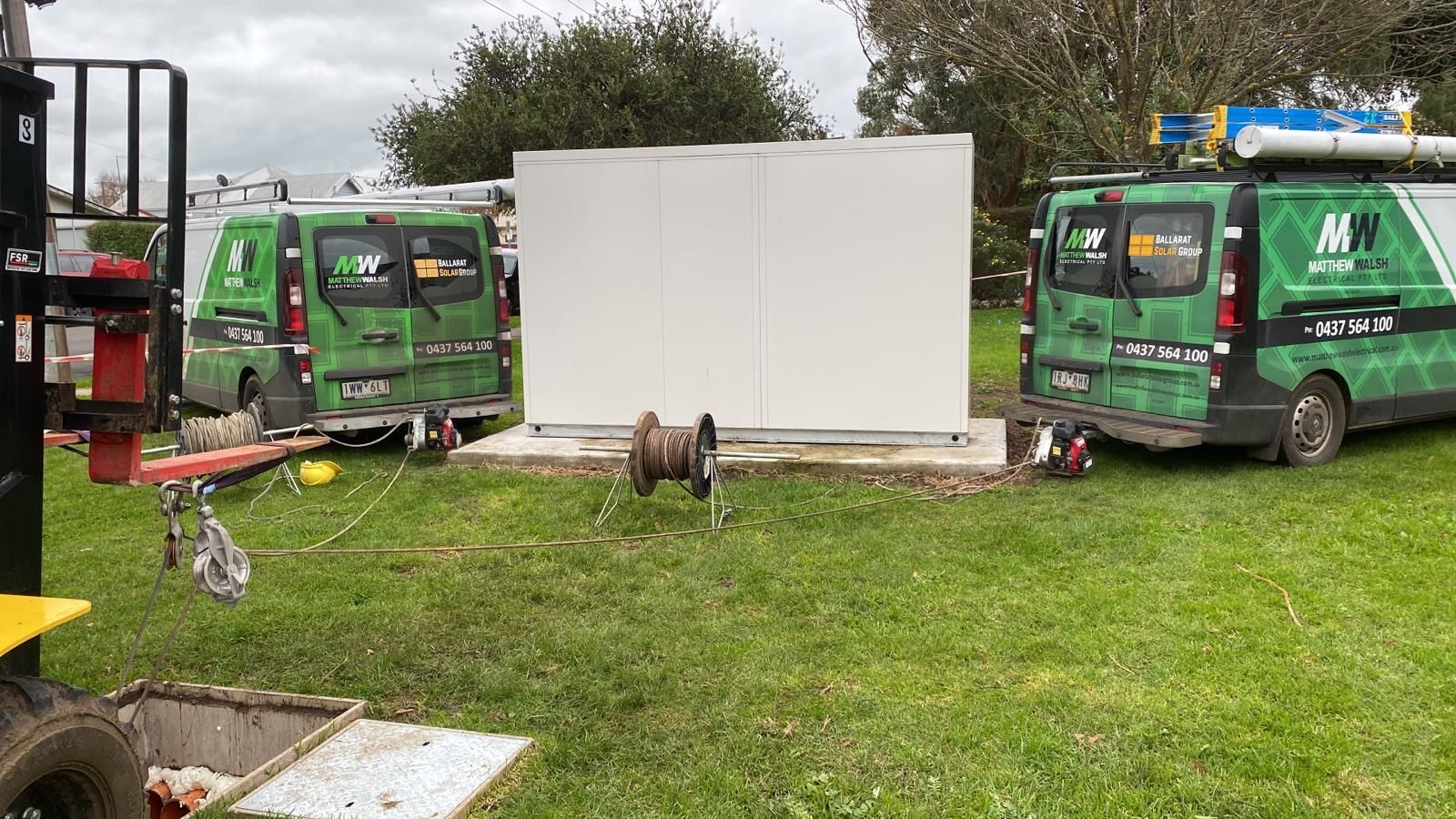 Two green vans are parked in a grassy field.