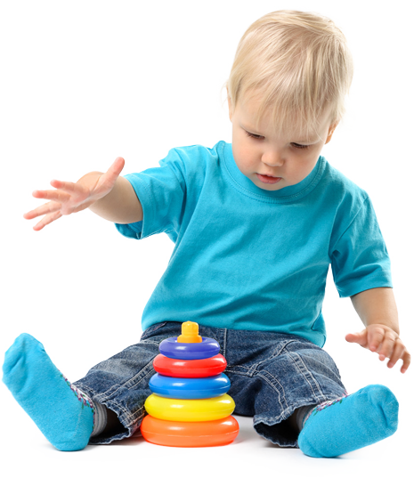 A toddler in a blue shirt and blue socks reaching toward a colorful plastic stacking toy against a white background.