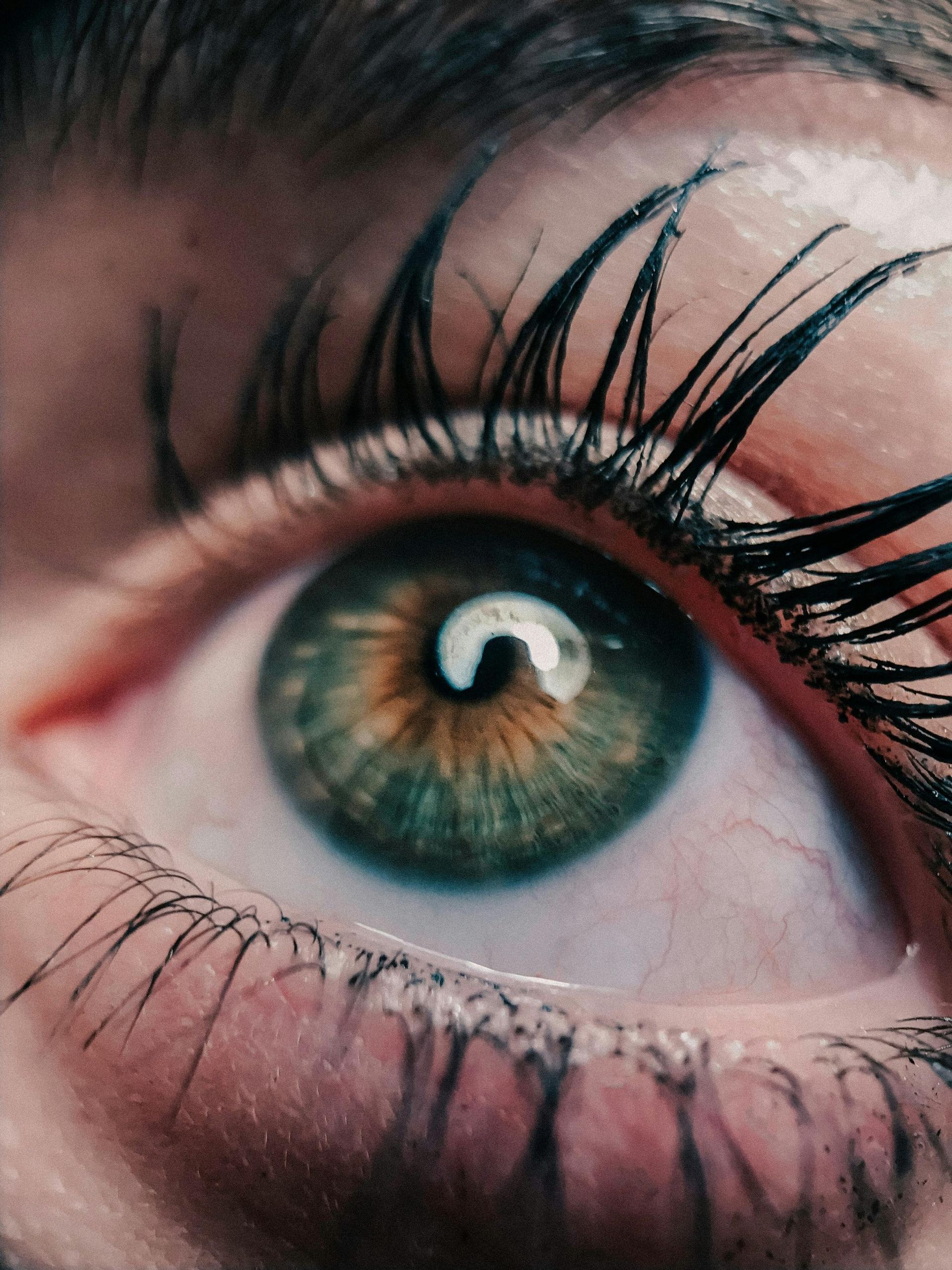 A close up of a woman 's green eye with long lashes