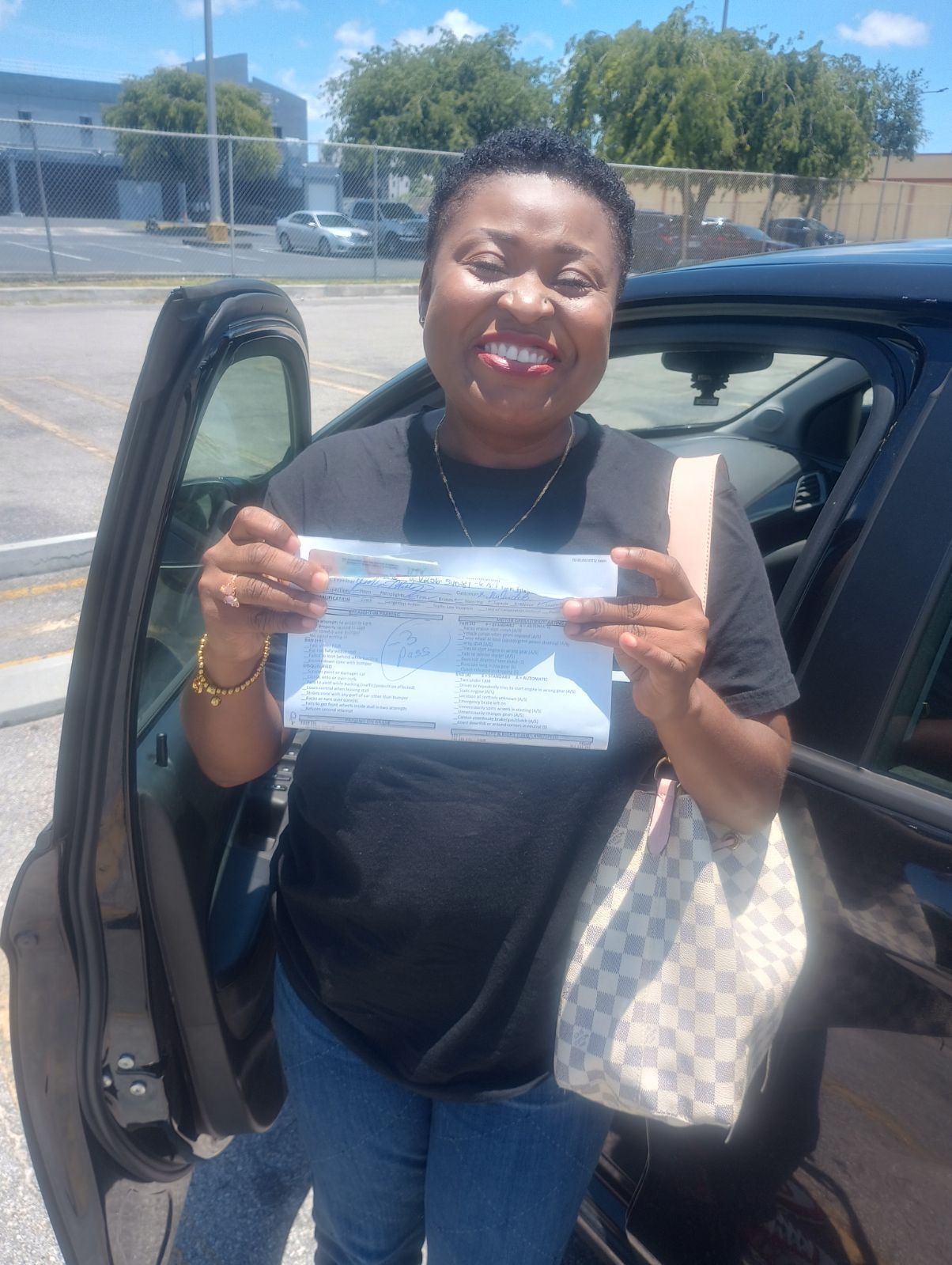 A woman is standing next to a car holding a driving license