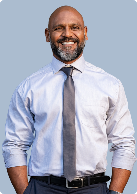 Smiling professional wearing a light blue dress shirt and a grey tie against a neutral background.