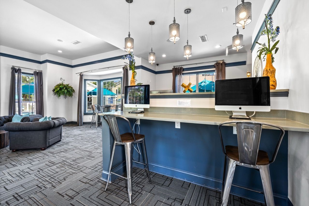 Community lounge with computer workstation, bar seating, and large windows.