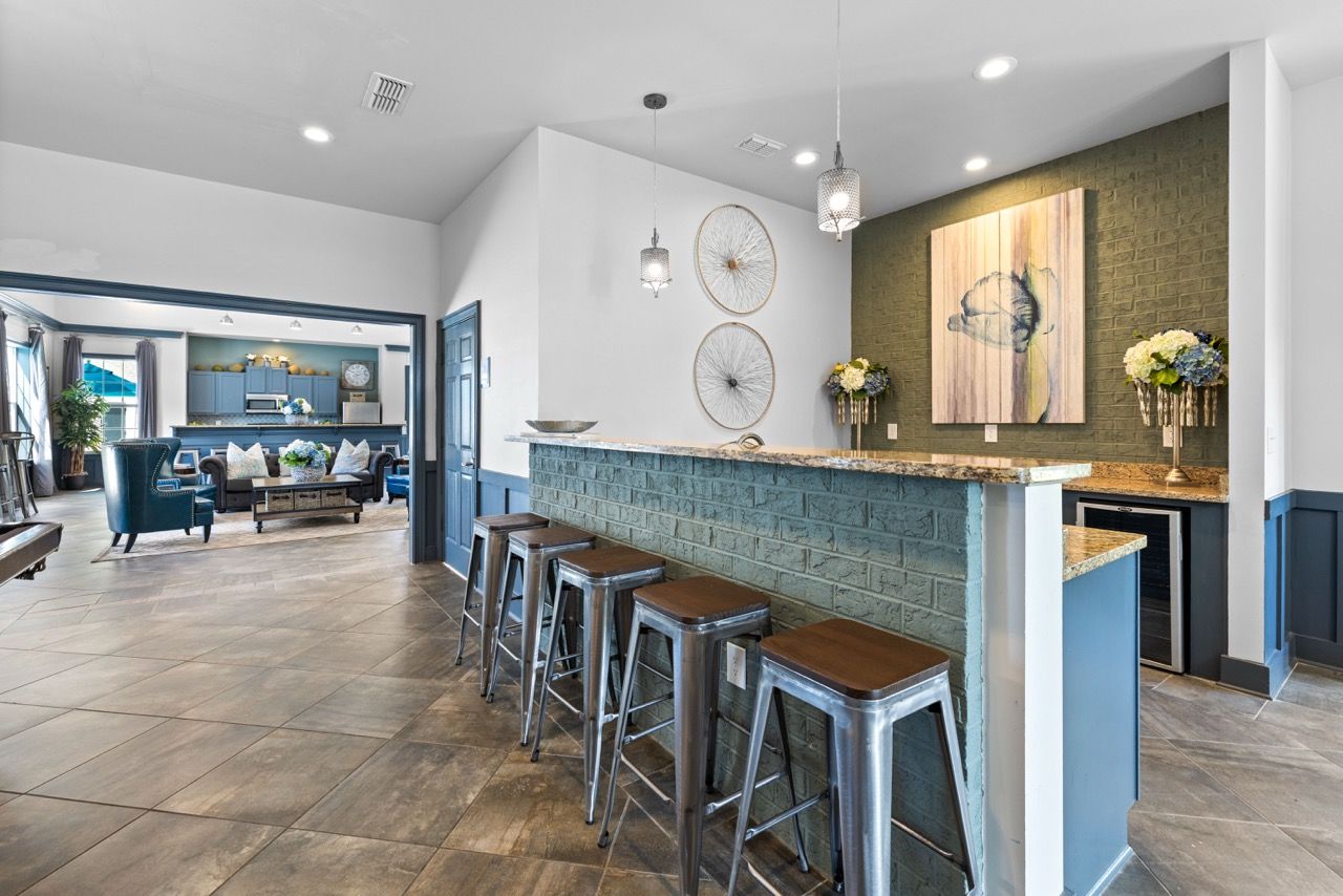 Communal lounge area with a bar-height counter, metal stools, and decorative wall art.
