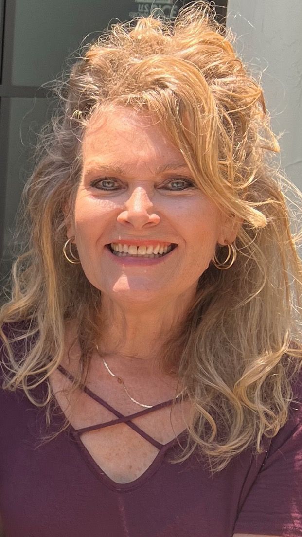 A woman in a purple shirt is smiling for the camera.