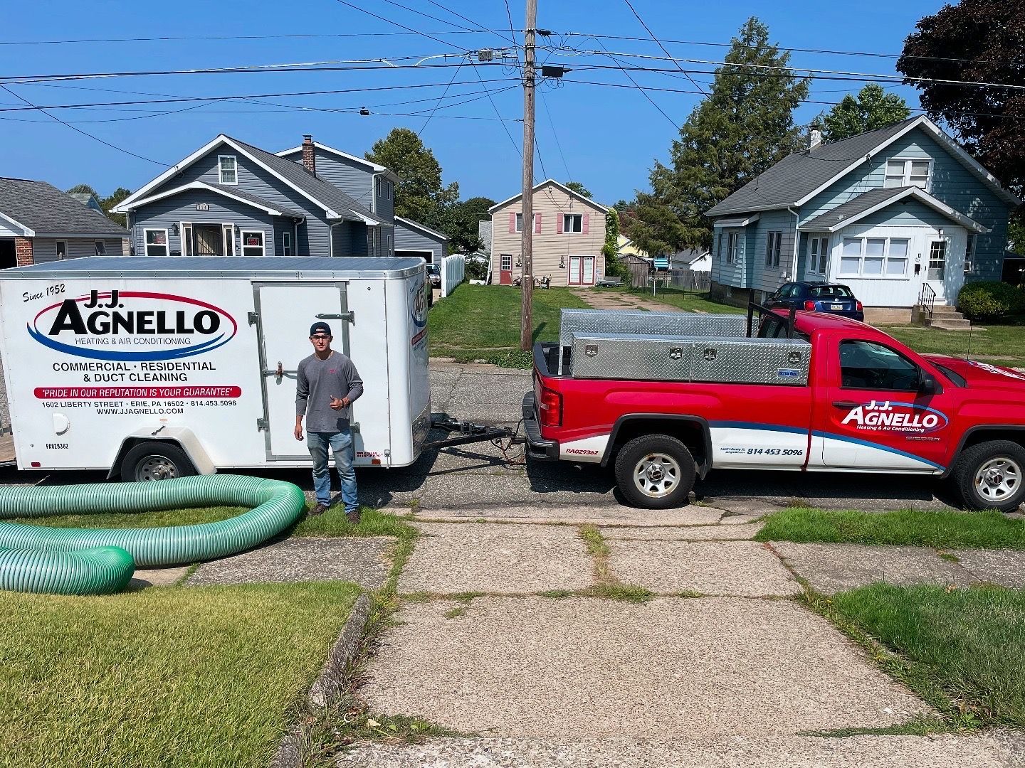 Coastal town with buildings on cliffs, a sandy beach, and a mountain backdrop; blue water and sky.