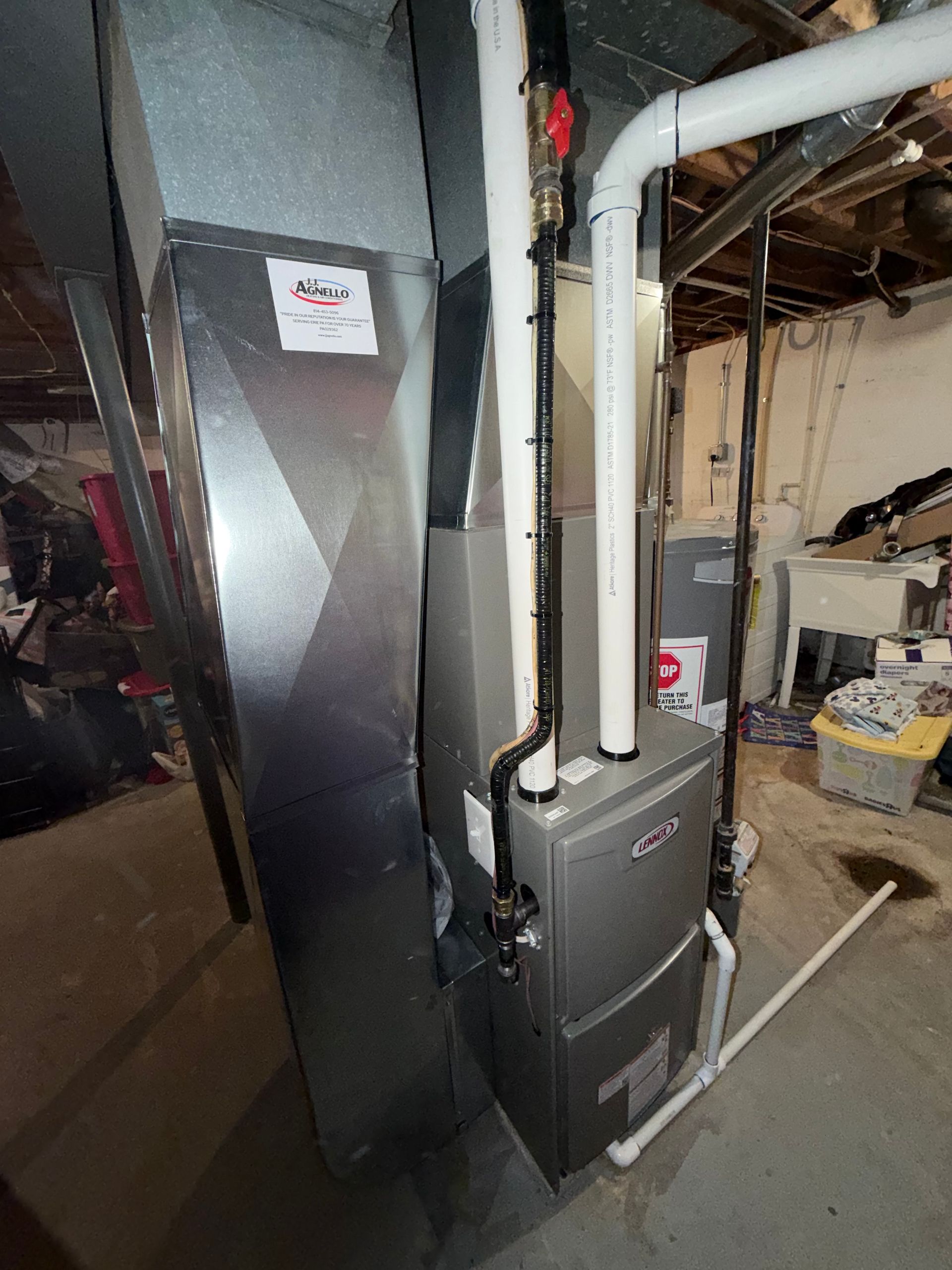 Woman in a black patterned dress looks at phone as barefoot girl in pink dress twirls in a sunny room.