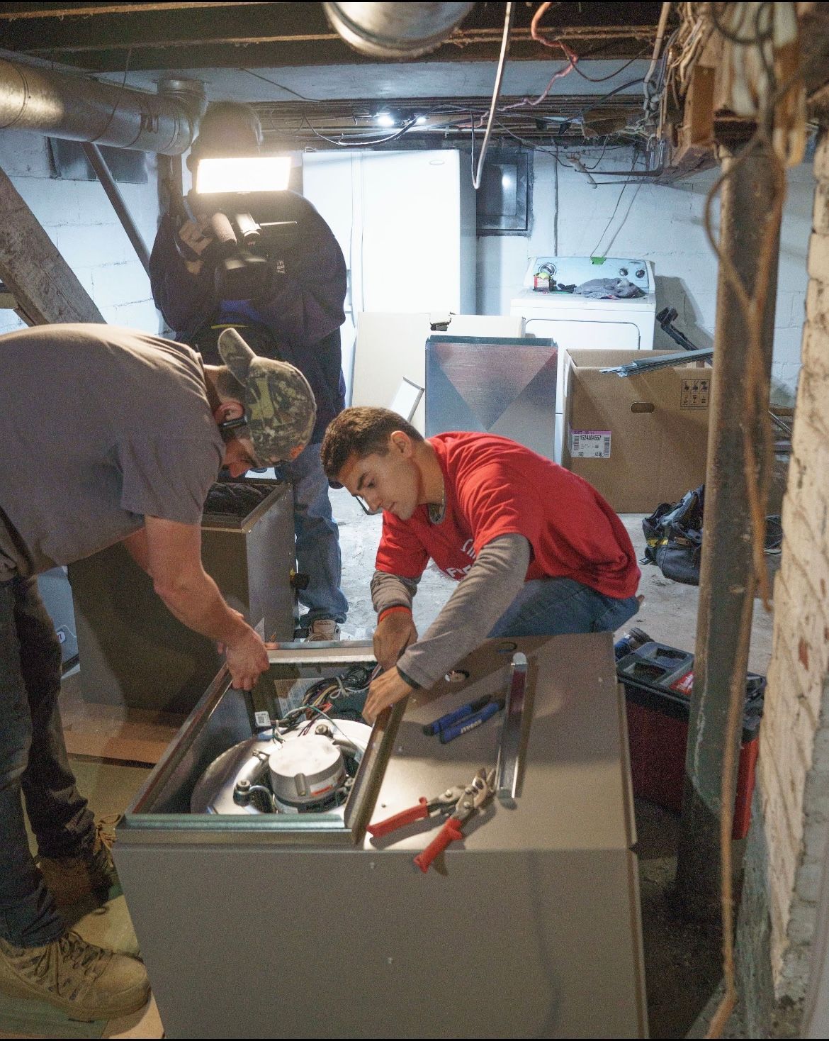 An HVAC technician connects gauges to an outdoor AC unit.