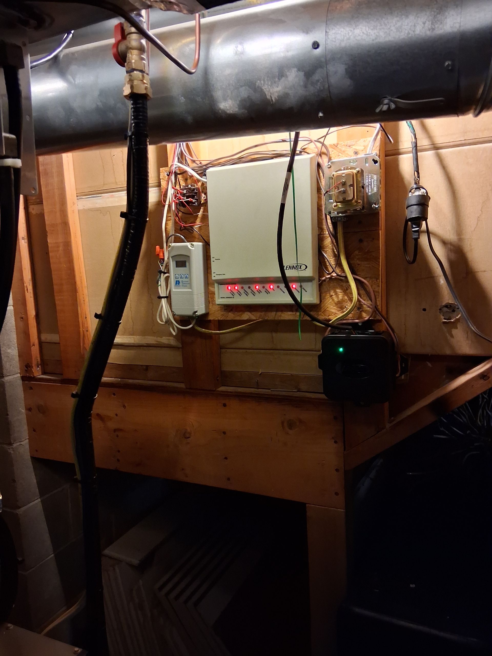 Electrical equipment mounted on wooden wall panels in a dimly lit basement, featuring illuminated status indicators.