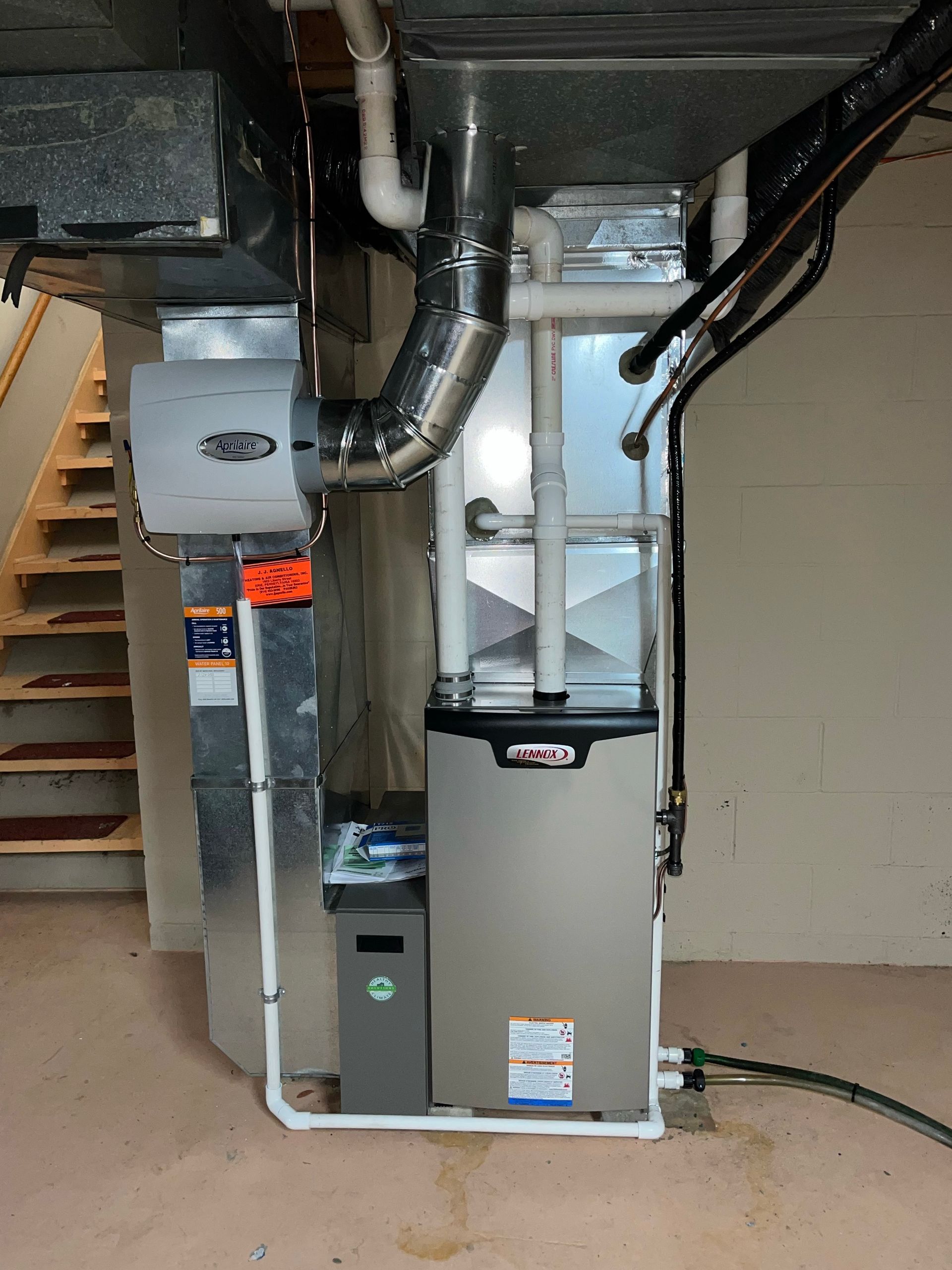 White gate and bridge leading to wooden stairs ascending a grassy hill under a cloudy sky.