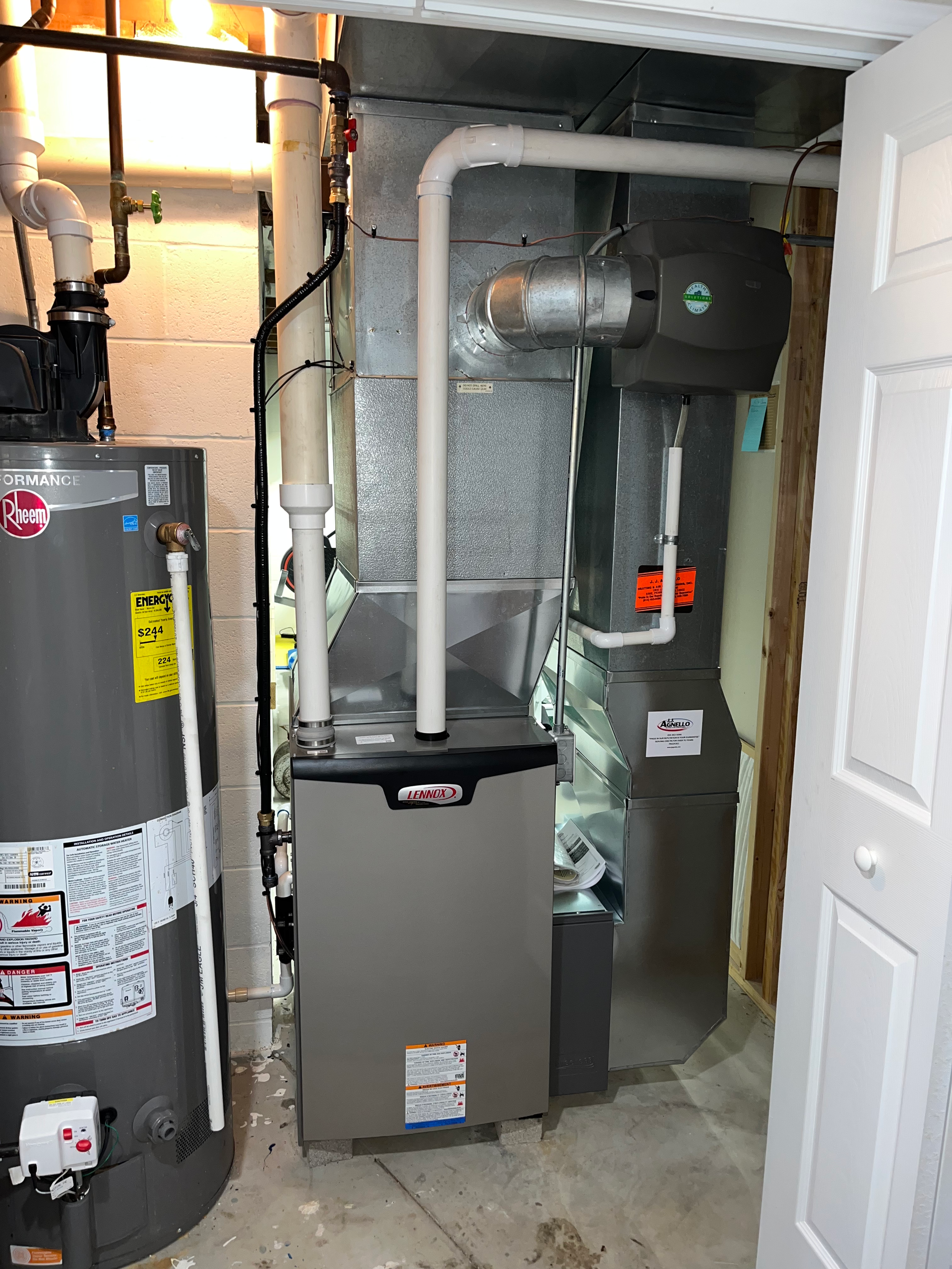 A gas furnace and a tall water heater installed in a utility closet with white paneled doors.