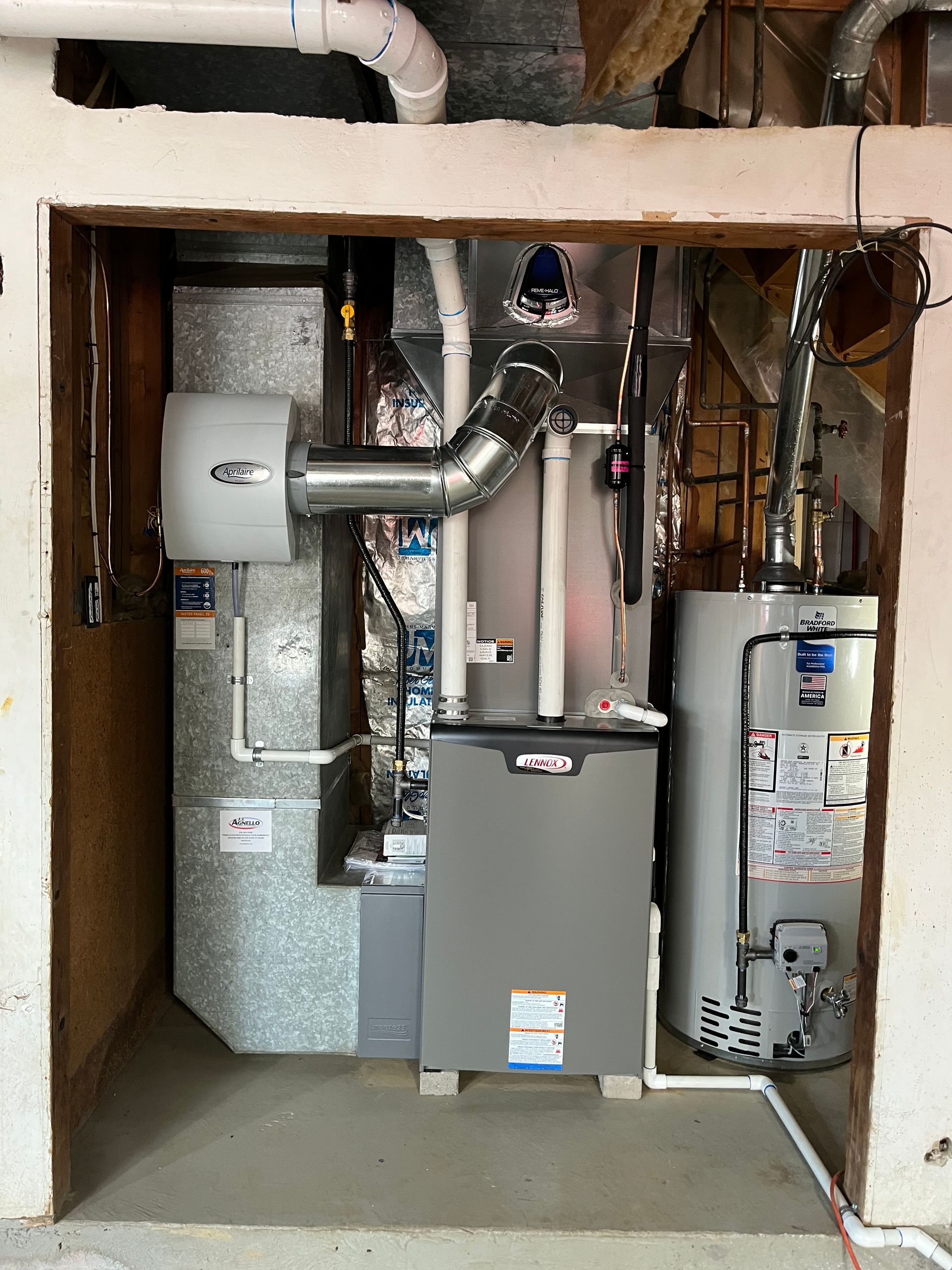 A utility closet containing a gas furnace, a tall water heater, and a white humidifier unit mounted on the ductwork.