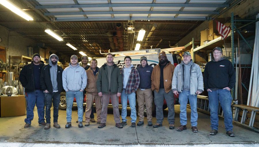 Group of workers posing inside a garage. Men are wearing casual clothing.