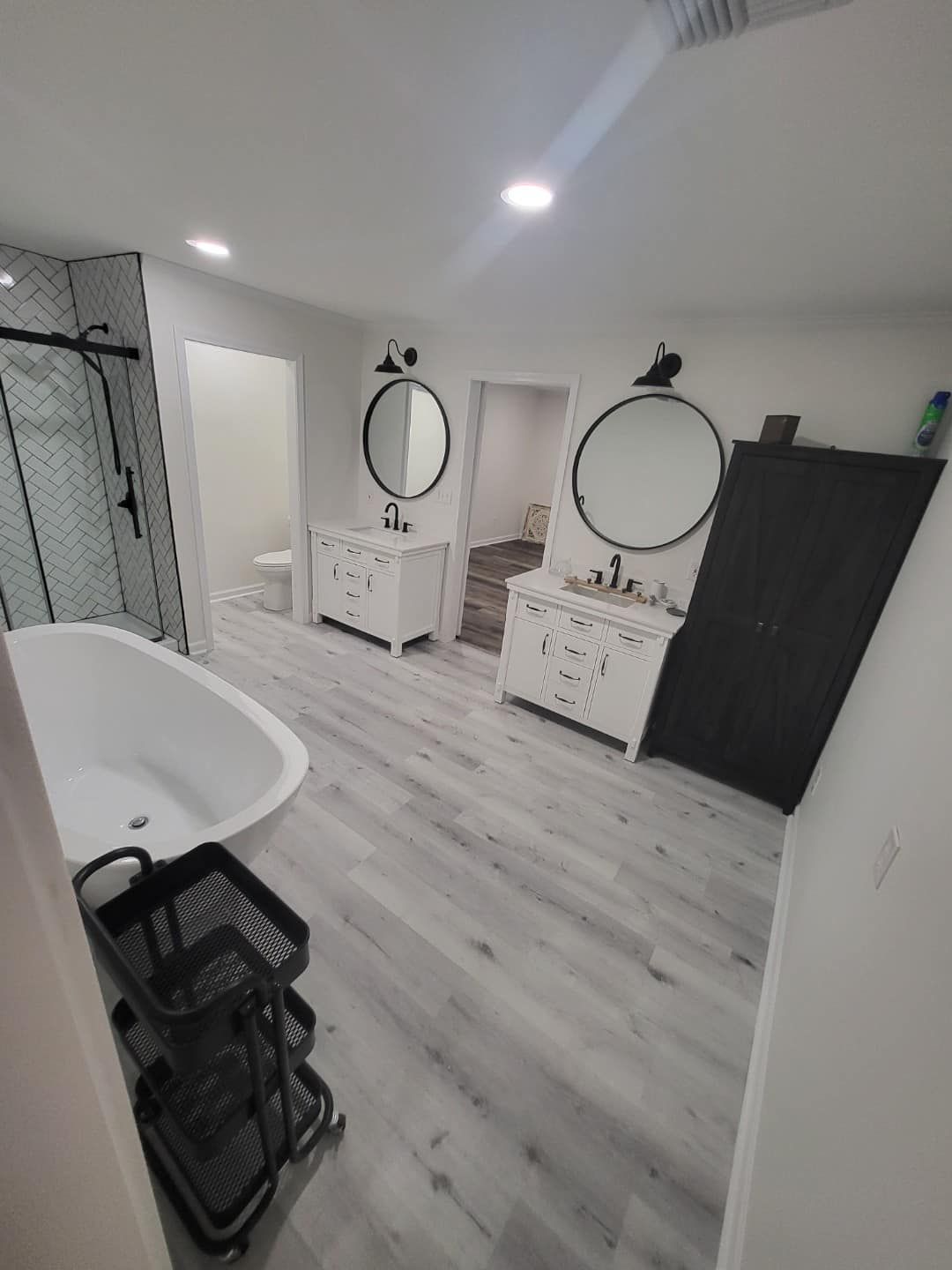 A bathroom with two sinks , two mirrors and a bathtub.