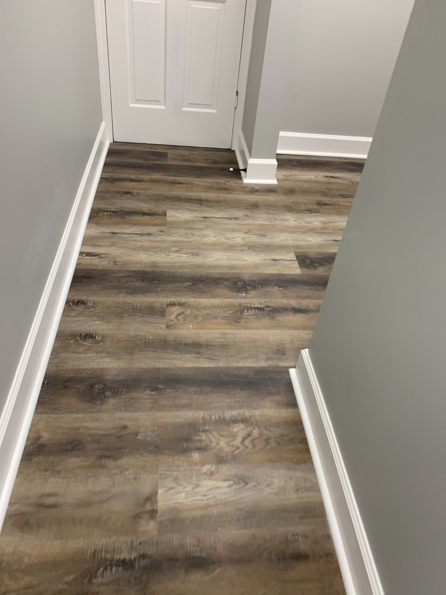 A hallway with a wooden floor and white trim.