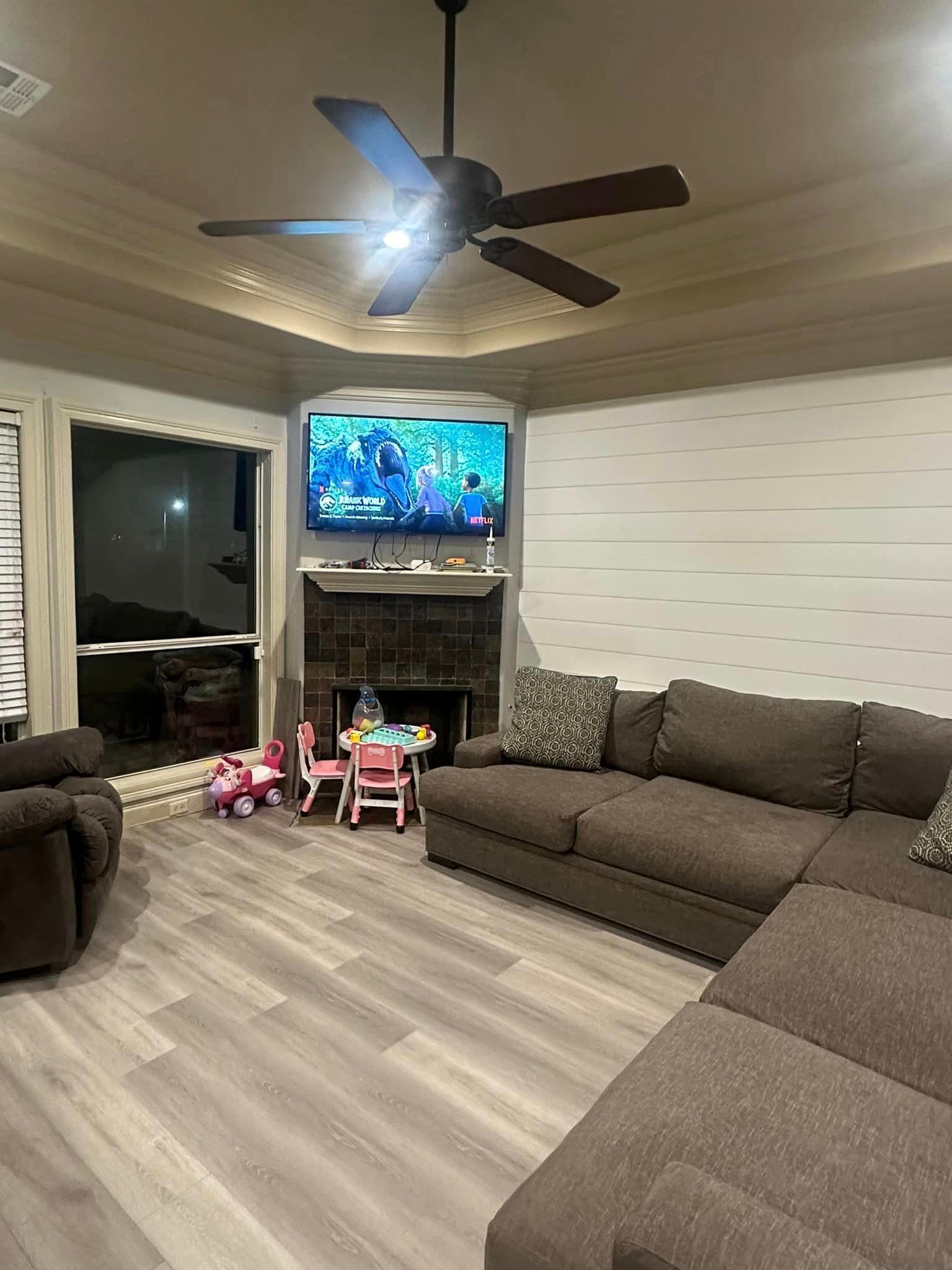 A living room with a couch , chairs , a fireplace and a ceiling fan.