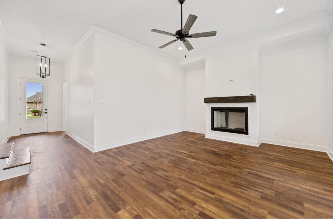 An empty living room with hardwood floors and a fireplace.