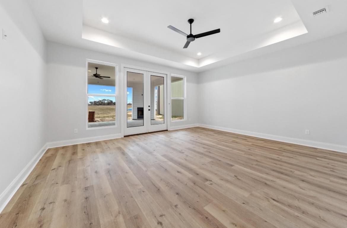 An empty living room with hardwood floors and a ceiling fan.