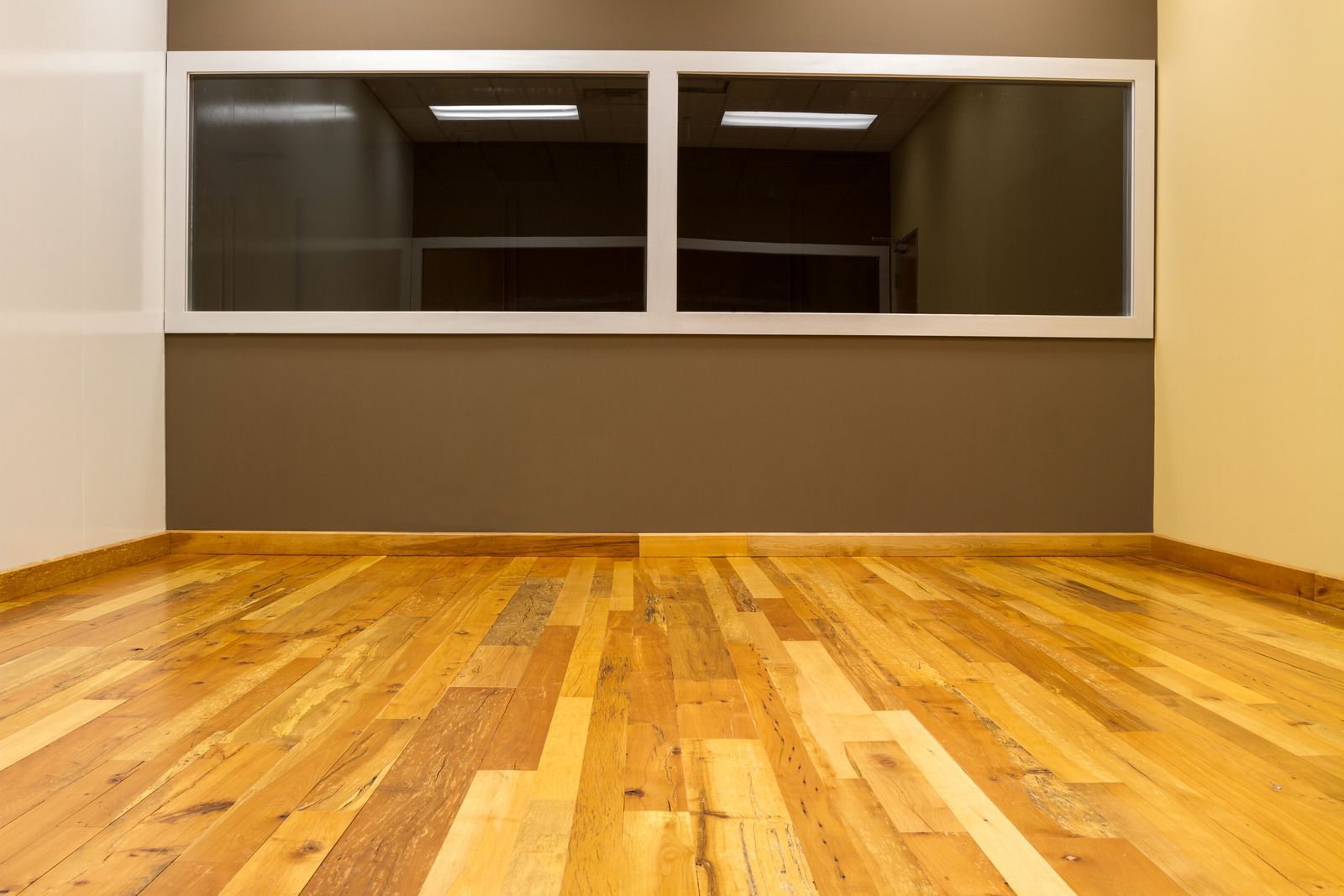 An empty room with a wooden floor and two windows