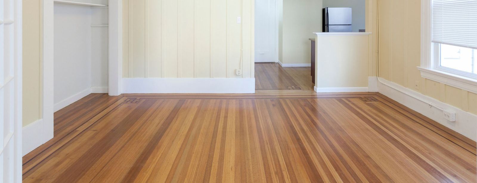 An empty room with hardwood floors and yellow walls.