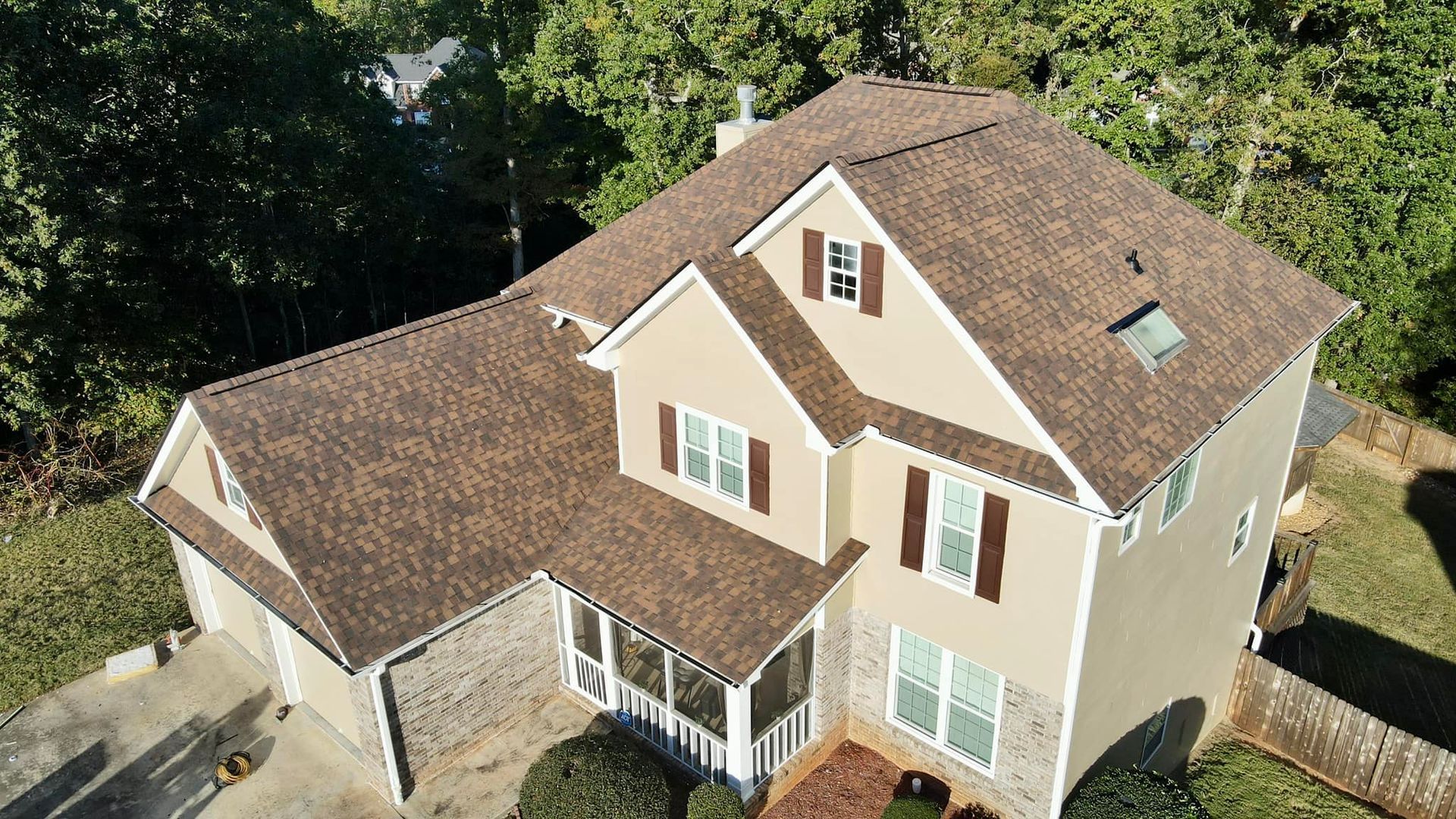 An aerial view of a large house with a brown roof surrounded by trees.