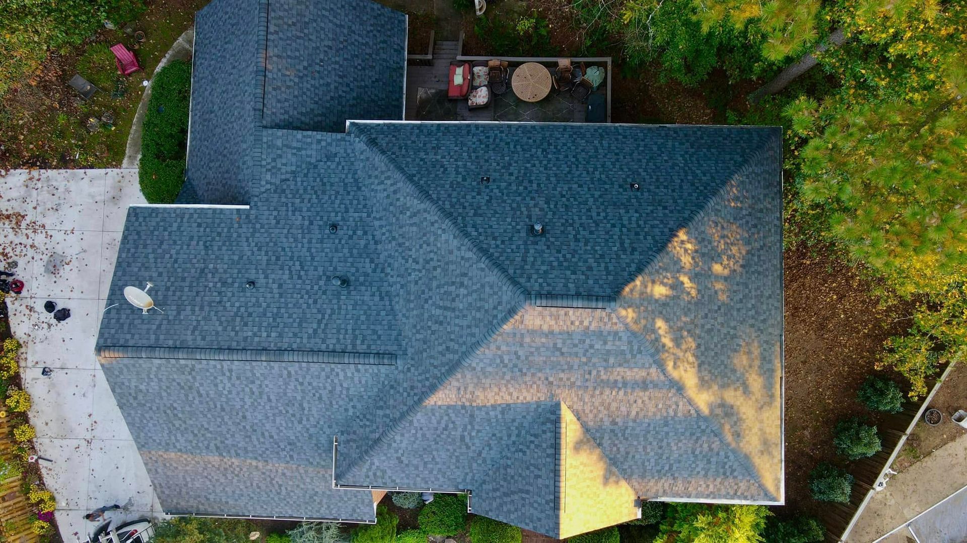 An aerial view of a house with a blue roof surrounded by trees.
