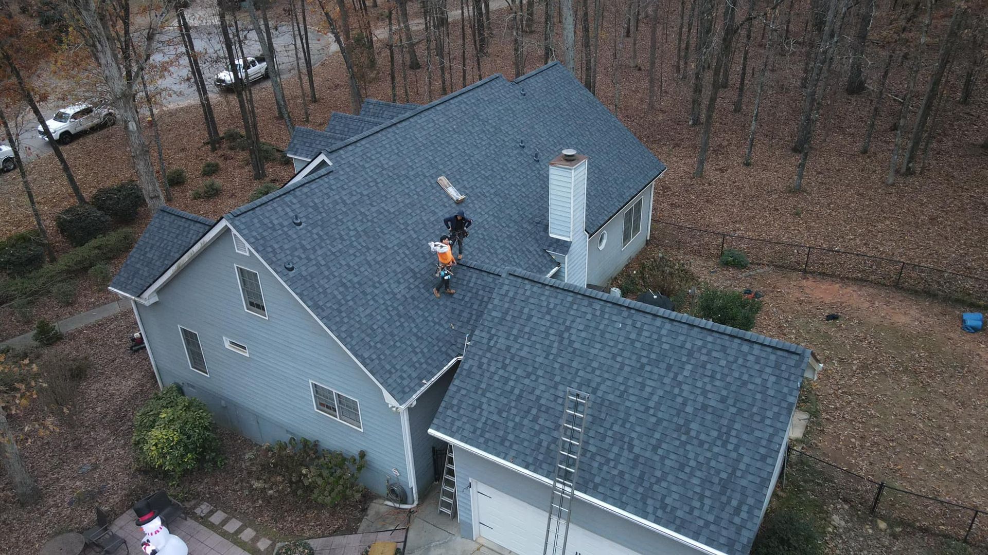 An aerial view of a house with a man on the roof.