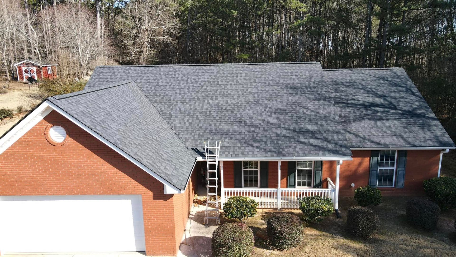An aerial view of a brick house with a black roof