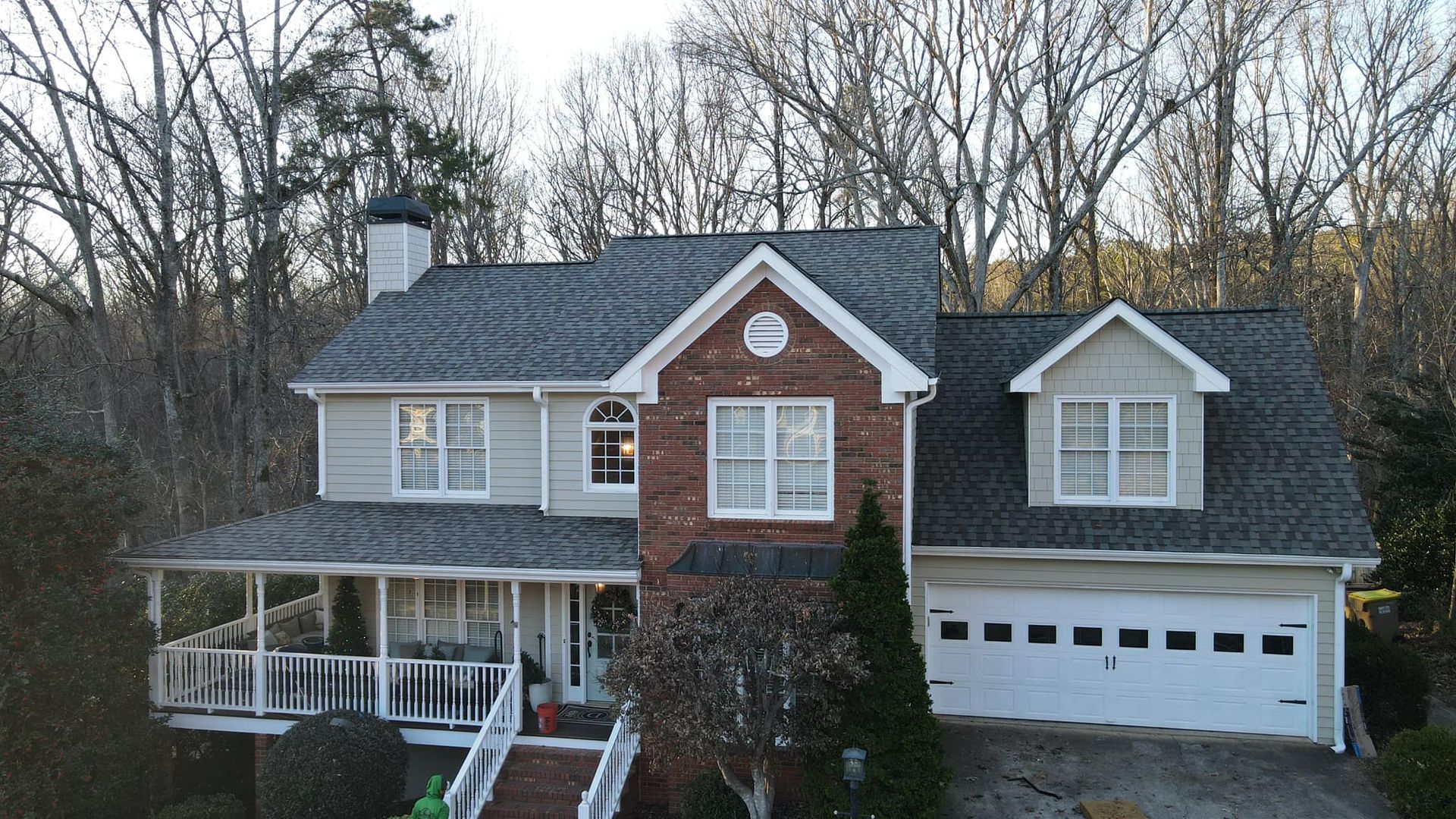 An aerial view of a large brick house with a gray roof