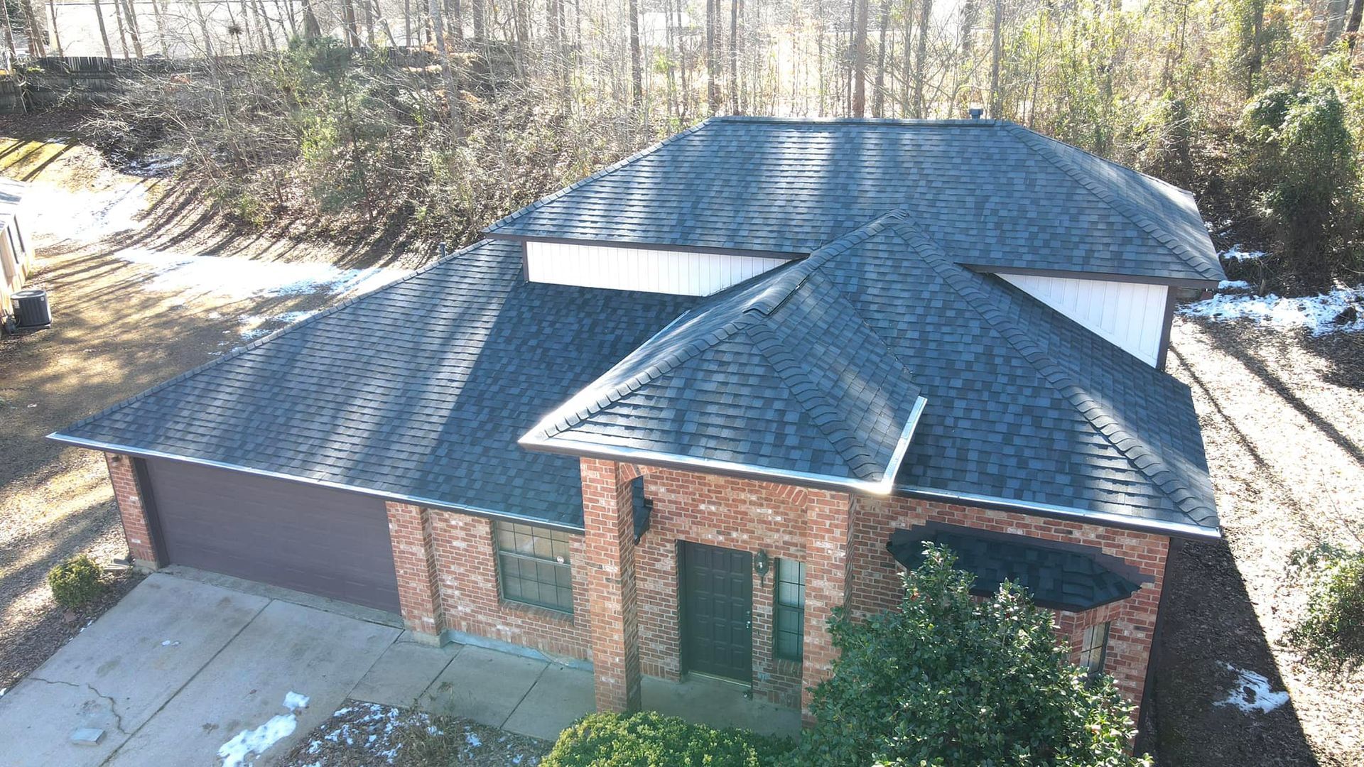 An aerial view of a brick house with a black roof.