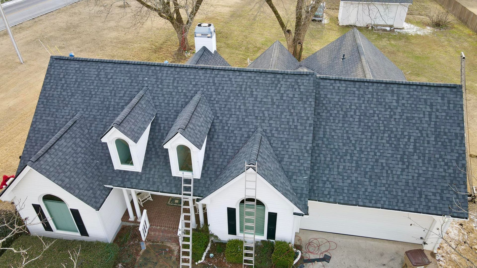 An aerial view of a white house with a black roof.