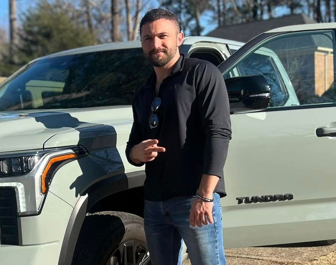 A man is standing in front of a white truck.