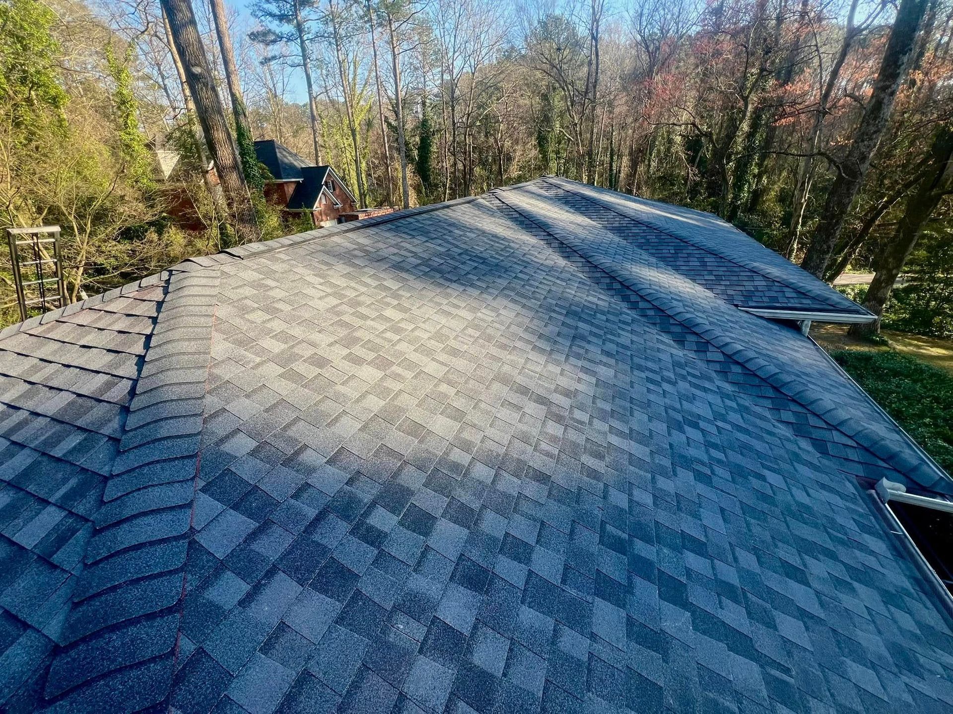 A roof with a lot of shingles on it is surrounded by trees.