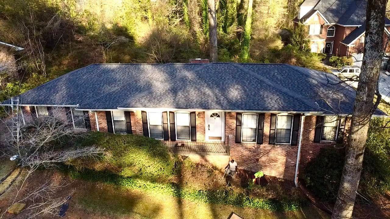 An aerial view of a house with a roof that is surrounded by trees.
