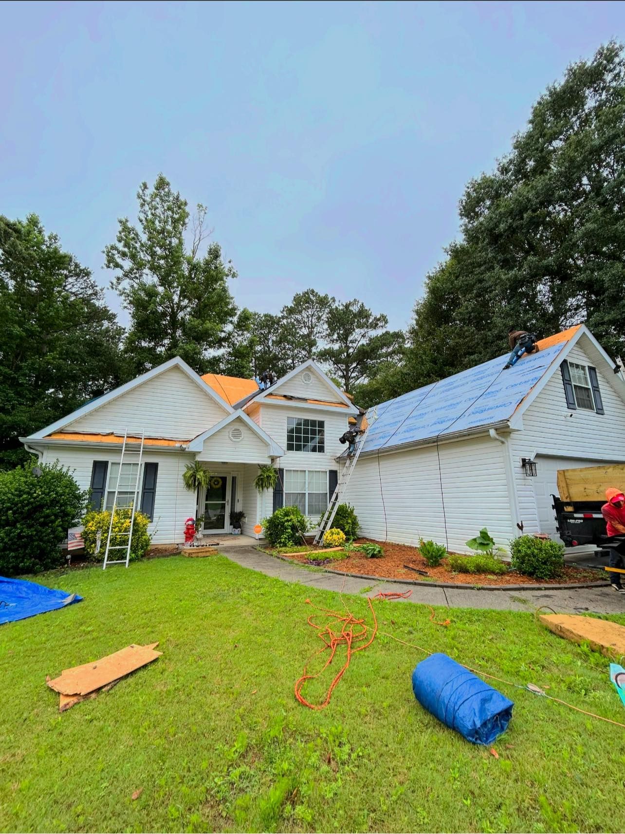 A white house with a blue roof is being remodeled.