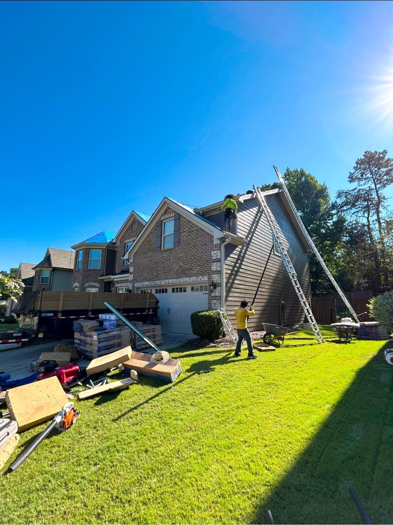 A man is standing on a ladder in front of a house.