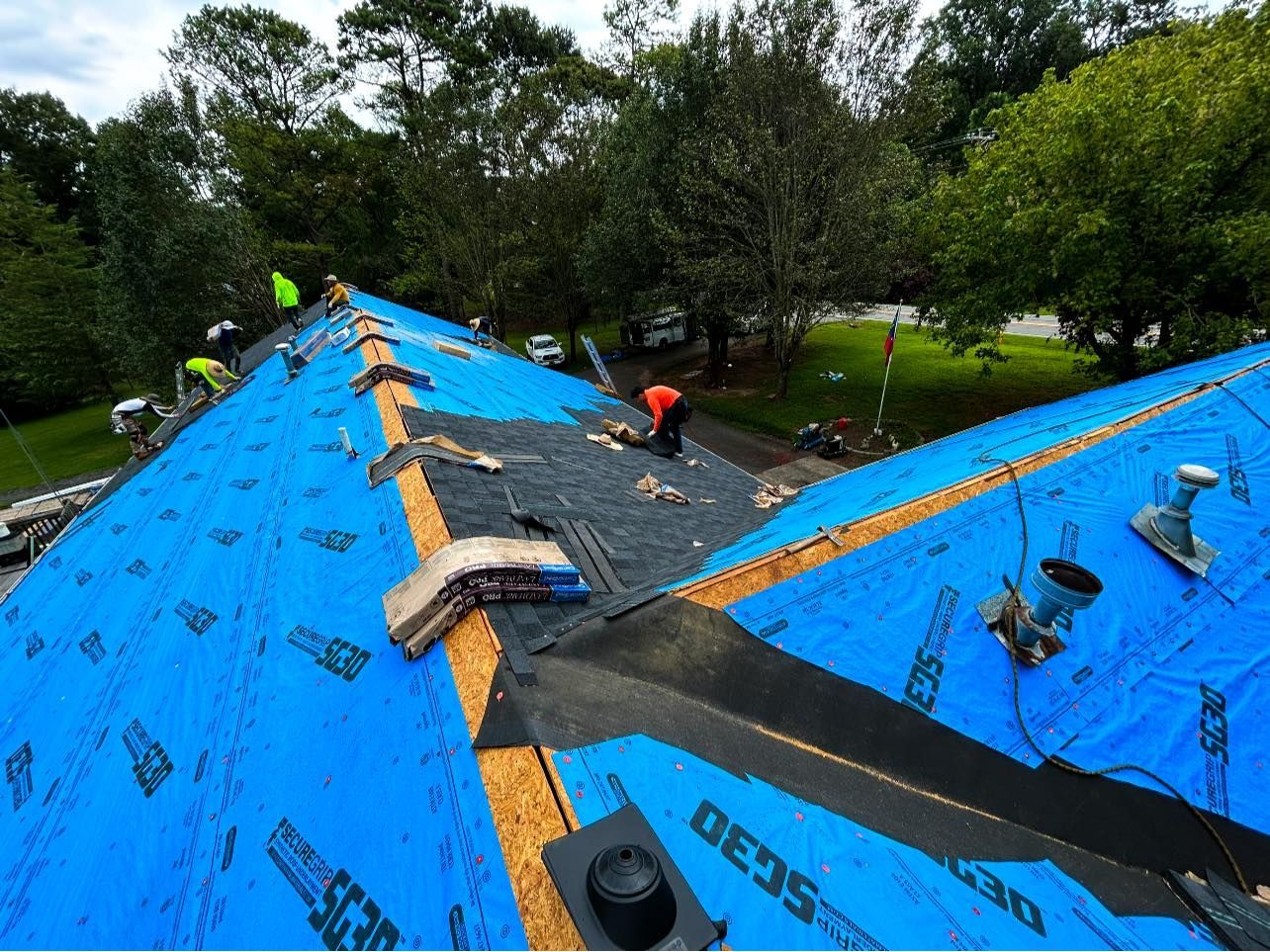 A man is working on a roof with a blue tarp on it.