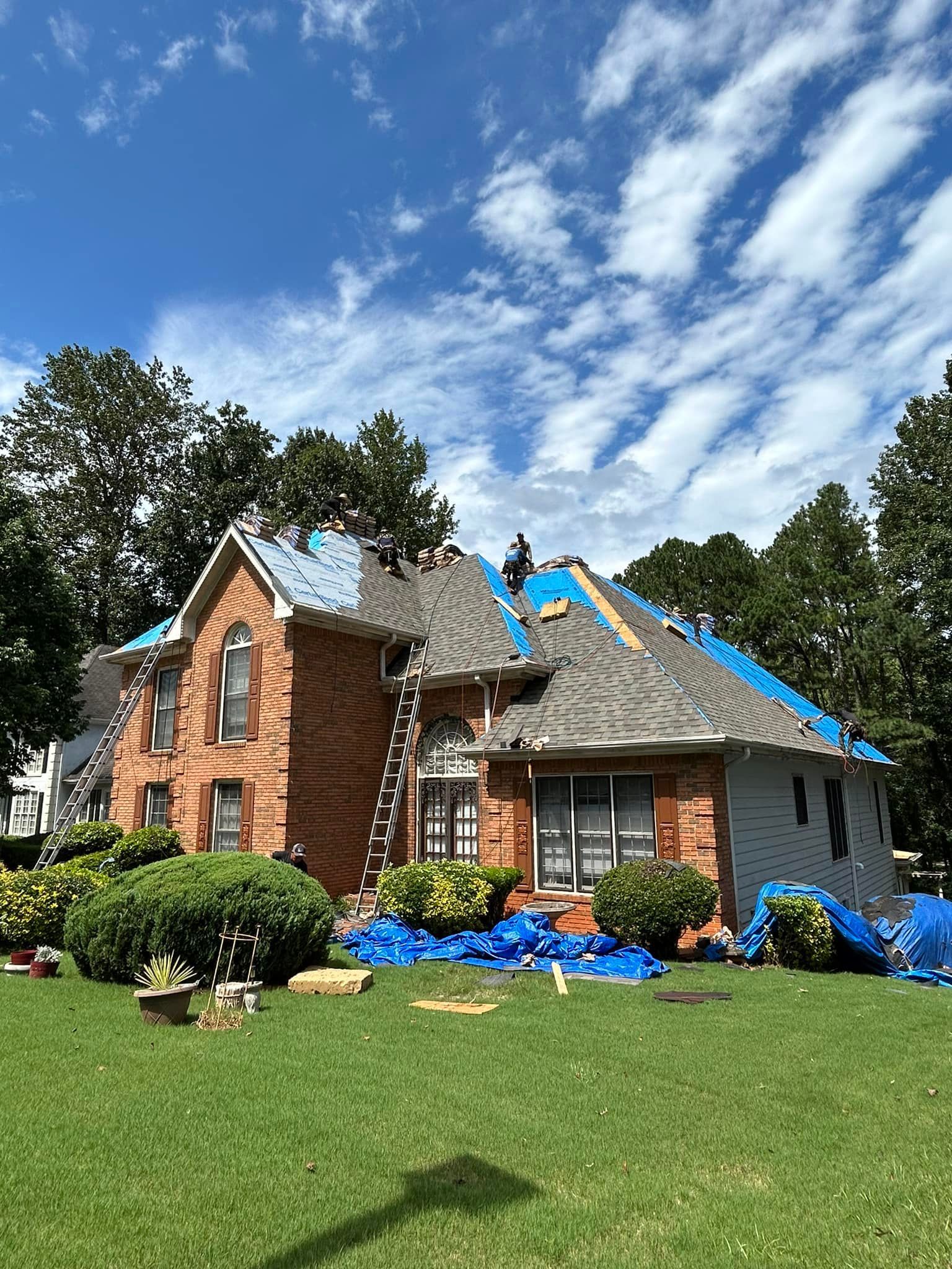 A large brick house is being remodeled with a new roof.