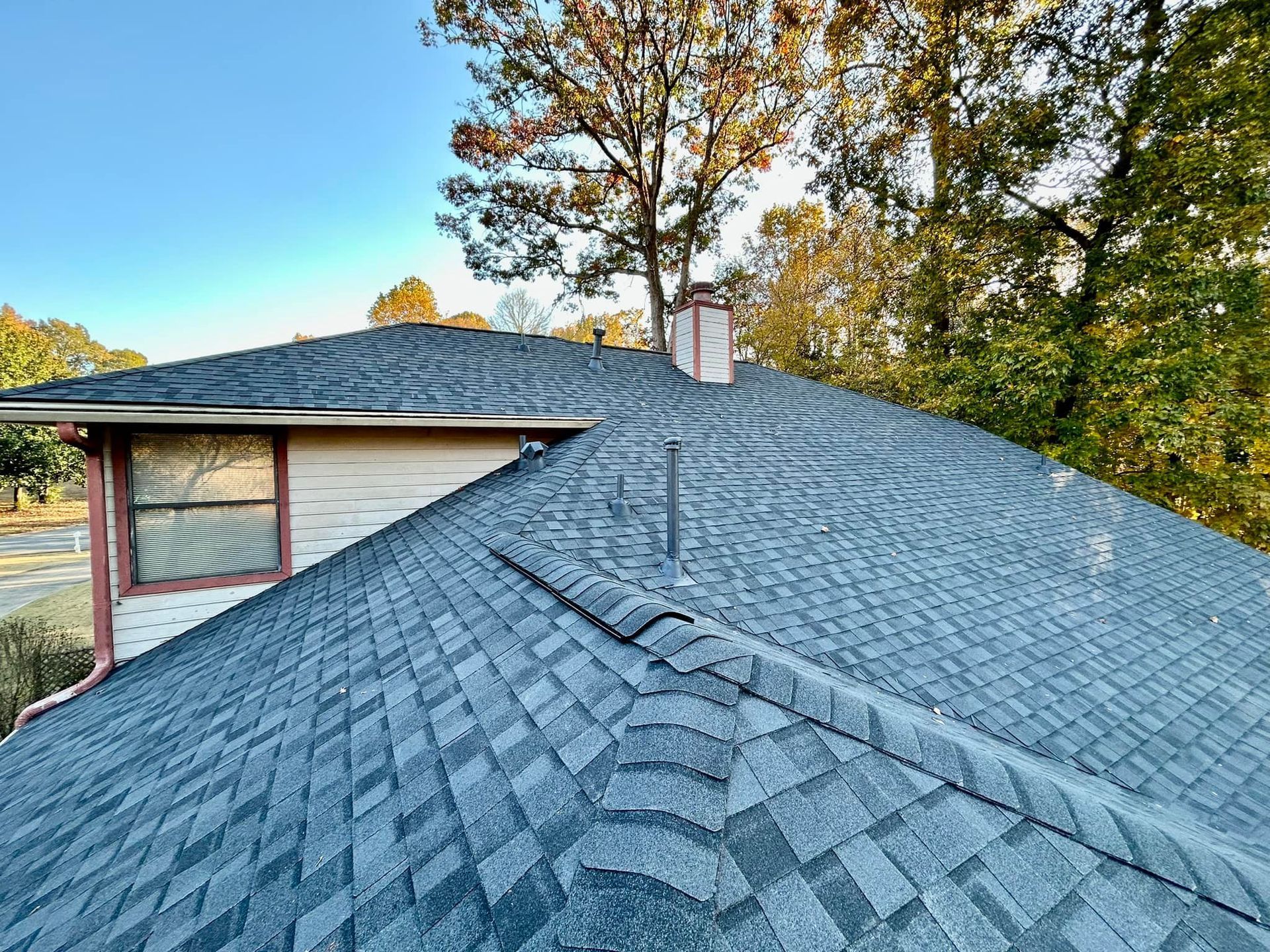 A close up of a roof of a house with trees in the background.