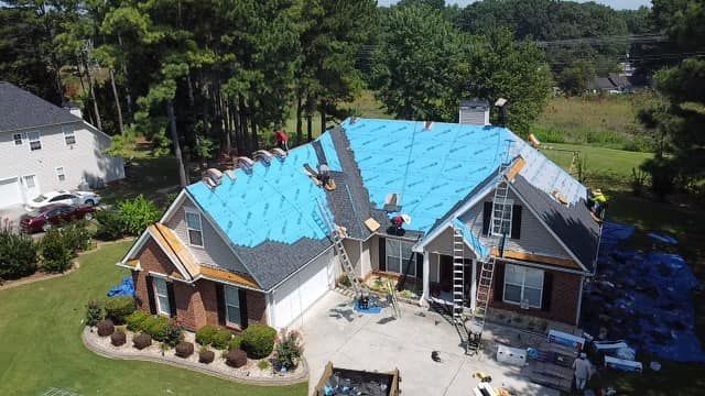 An aerial view of a house being remodeled with a blue roof.