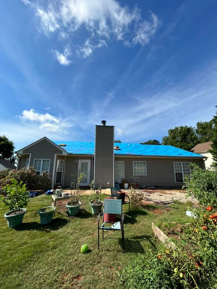 A house with a blue tarp on the roof is being remodeled.