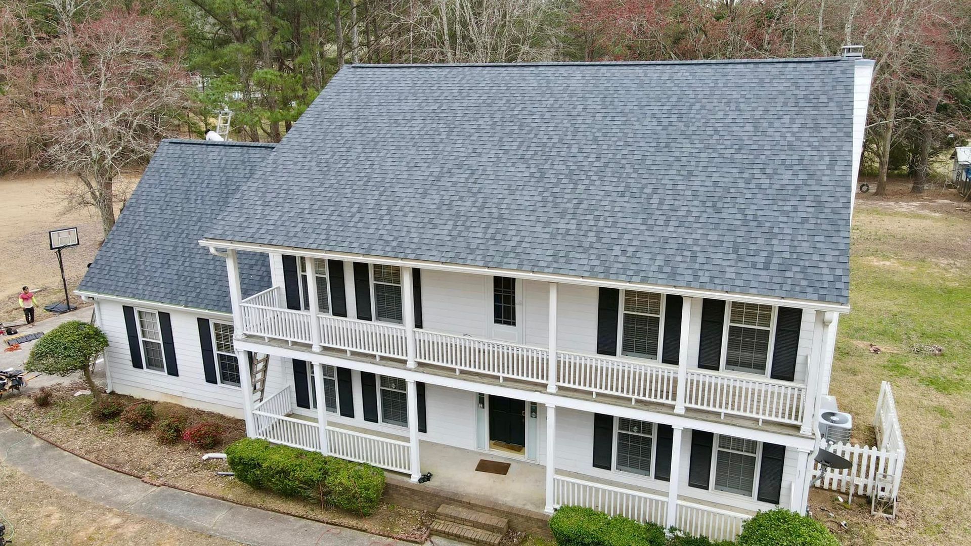 An aerial view of a large white house with a blue roof.