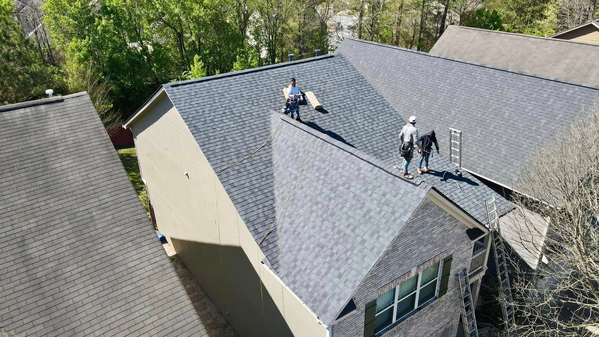 Two men are working on the roof of a house.