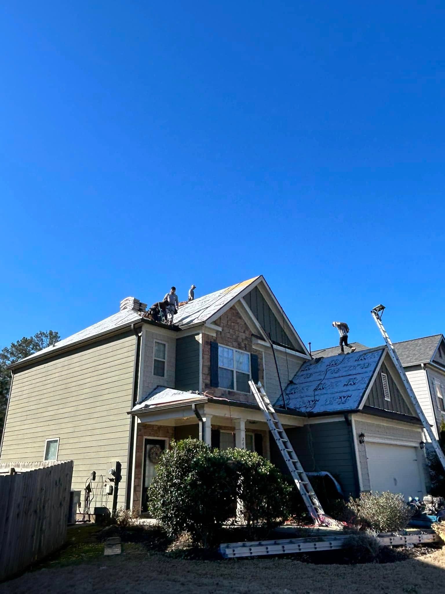 A group of people are working on the roof of a house.