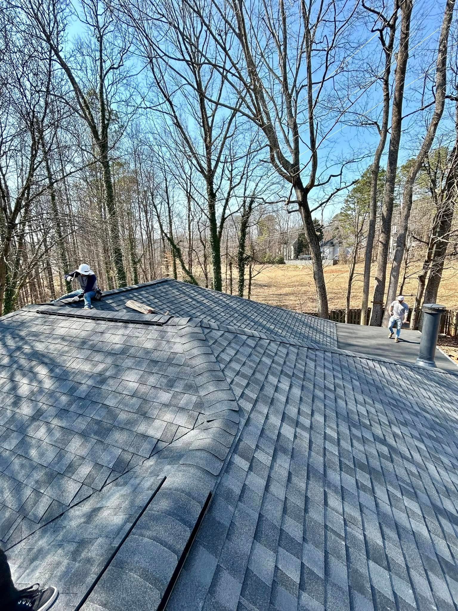 A roof with a lot of shingles on it and trees in the background.