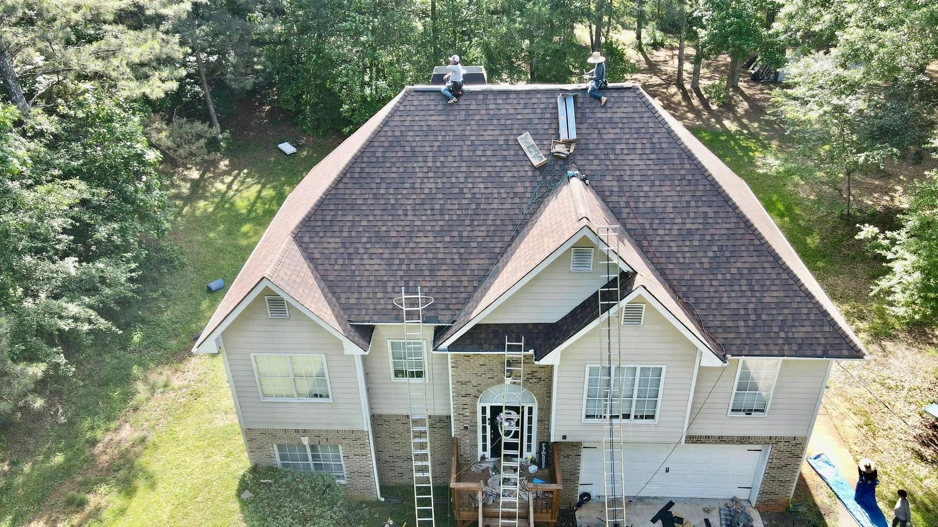 An aerial view of a large house with a roof being installed.