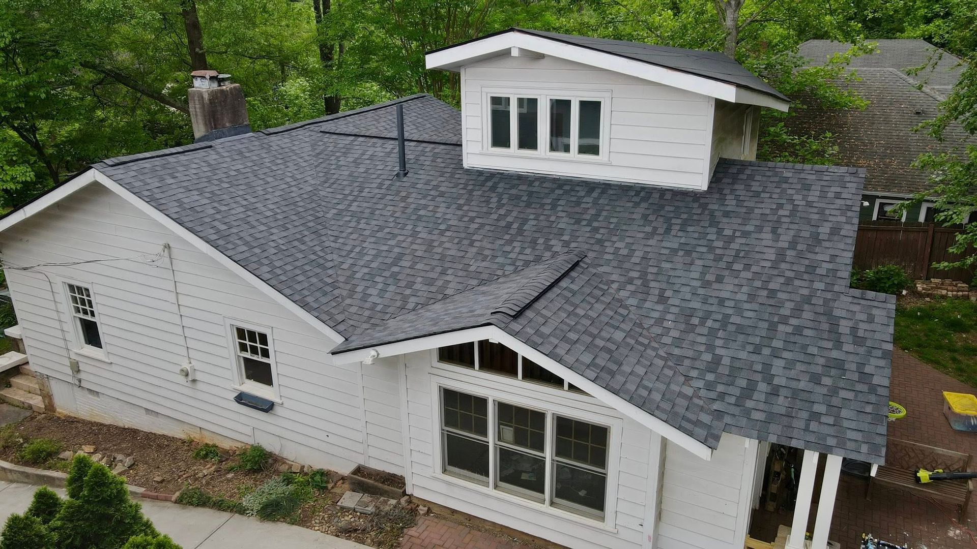 An aerial view of a white house with a black roof.