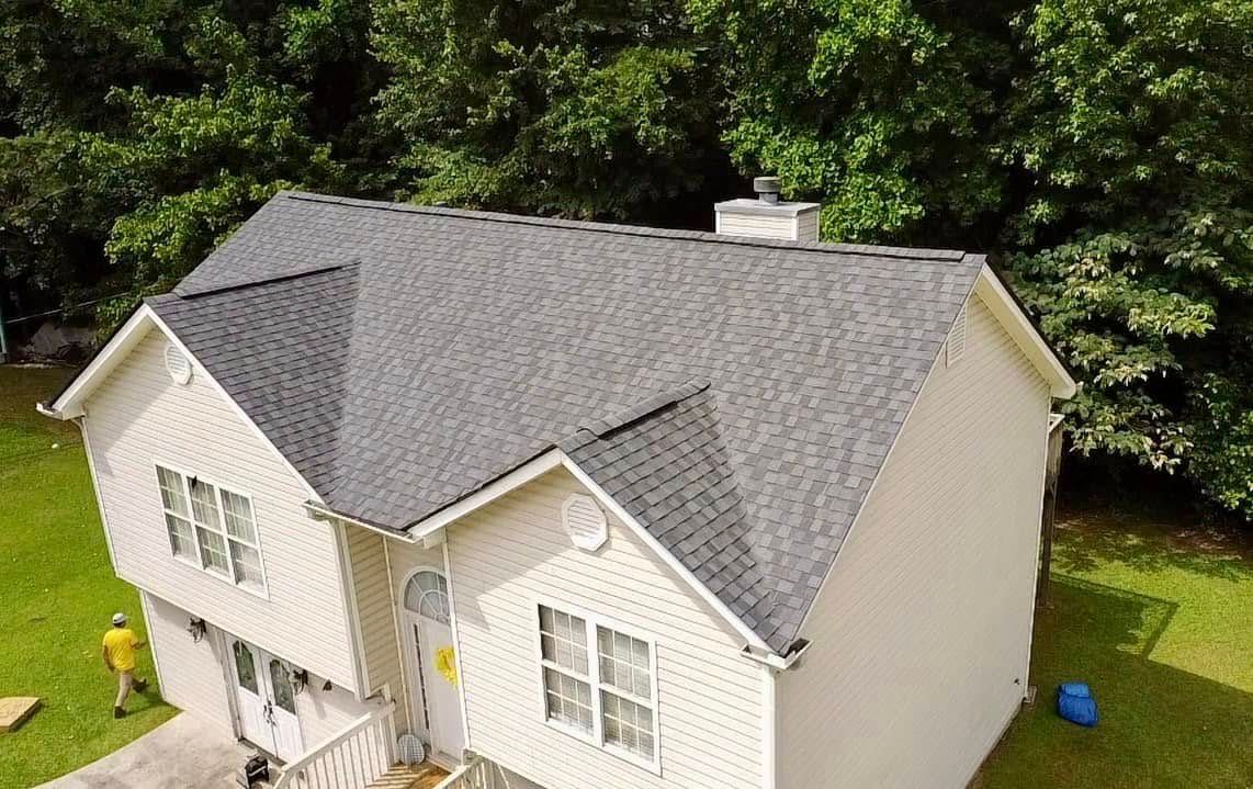An aerial view of a white house with a gray roof.