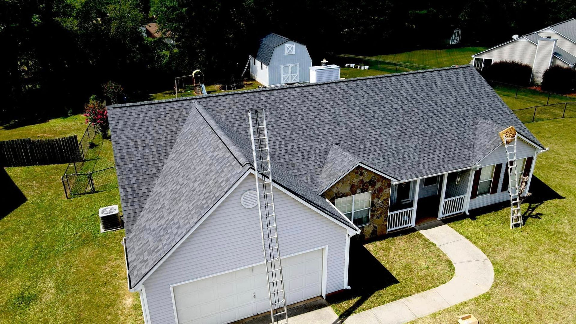 An aerial view of a white house with a gray roof.
